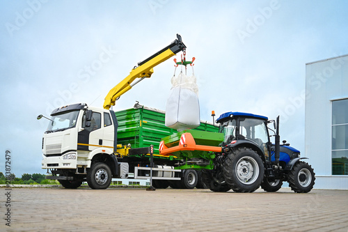 Truck loading fertilizer into a fertilizer spreader mounted on a tractor during agricultural field preparation. Modern machinery used for efficient fertilizer handling and crop nutrition.