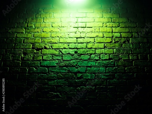 Brick wall photo illuminated by bright green light in the dark, moody interior architectural background