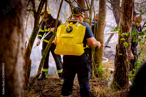 Firefighters using a backpack fire pump, water bag