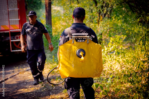 Firefighters using a backpack fire pump, water bag