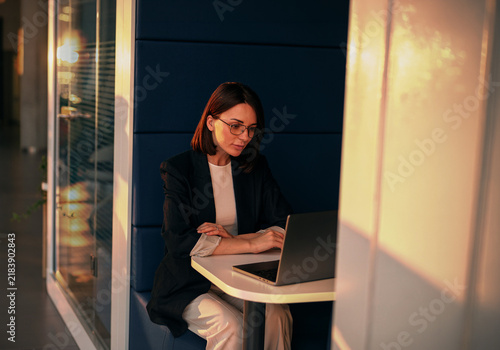 Businesswoman working on a laptop in an office phone booth