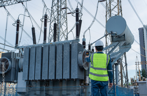 Bild auf Leinwand Engineer performs electrical safety inspection with a thermal camera on a power transformer in a high voltage substation, supporting fault detection and reliable operation