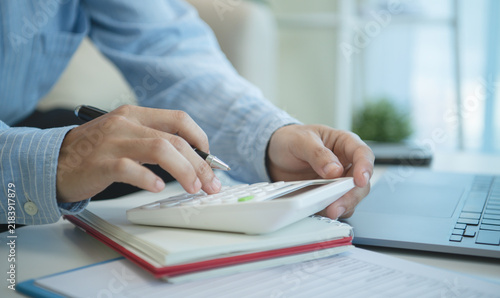 Business professional using calculator beside laptop for financial accounting budget planning expense analysis tax preparation cash flow control and accurate business management.