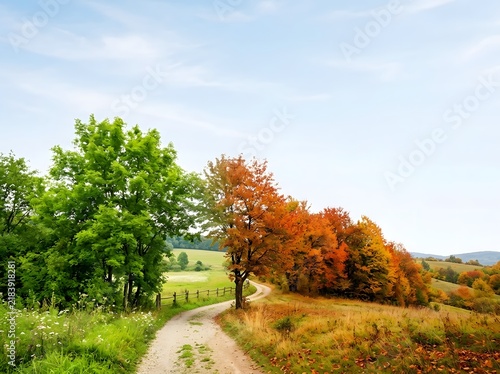 Conceptual landscape showing the transition from summer to autumn with vibrant green trees on the left and orange foliage on the right along a winding dirt road and rural hills.