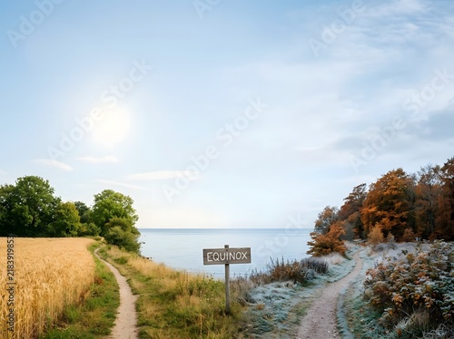 Split landscape showing seasonal transition; left side has golden fields, right side has frost and autumn leaves, with a central wooden Equinox sign overlooking a calm coastal sea.