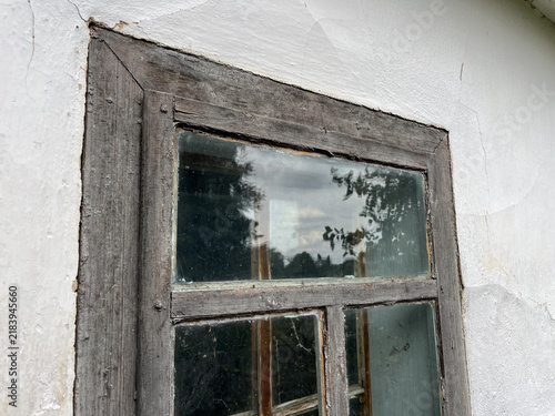 Horizontal low angle shot of an old weathered wooden window frame on a white stucco wall with glass reflection