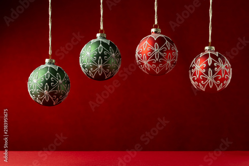 Red And Green Christmas Ornaments Hanging Against A Deep Red Festive Backdrop