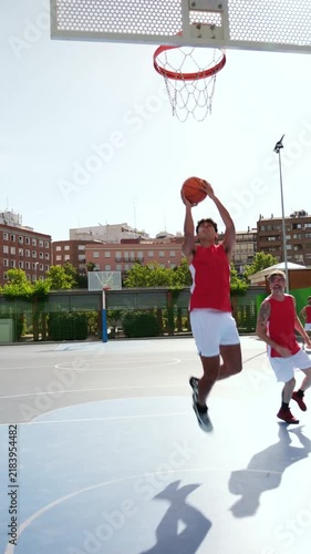 Athletic man scoring a layup during a training session with his teammates on an urban court