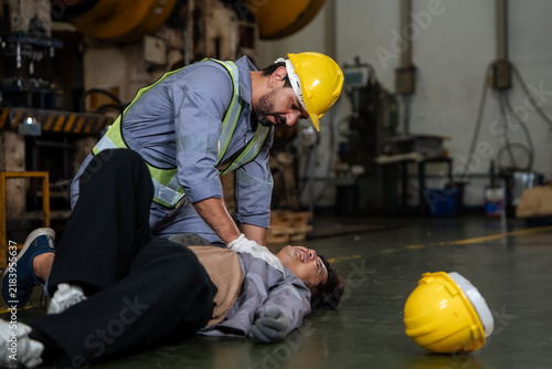 Foto Worker performs CPR on a person lying on factory floor