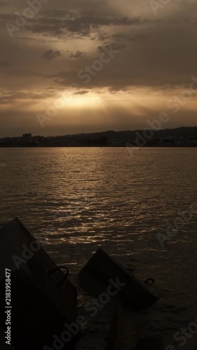 Golden sunset over calm sea with concrete blocks in 4k vertical format