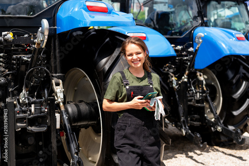 Portrait of a female mechanic standing in front of tractors outdoors