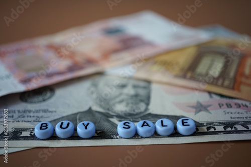 A dollar and euro bill and the inscription sell, buy.
