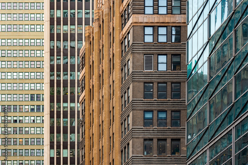 Geometric textures and architectural patterns of historic brick and modern glass buildings create a layered visual design across skyscraper facades in Manhattan, New York.