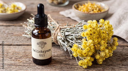 Helichrysum arenarium essential oil bottle with dried medicinal herb plant and flowers
