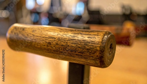 Detailed close up of a worn wooden handle with visible grain and a metal screw fixture