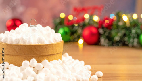 Fluffy white marshmallows piled in a wooden bowl with festive Christmas decorations and bokeh lights in the background