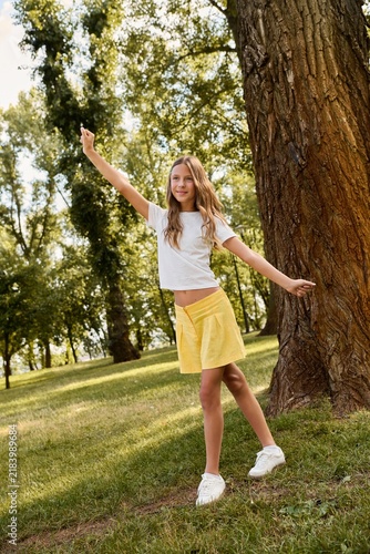 Happy girl enjoying a sunny day in a green park with cheerful energy