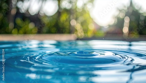 Dynamic blue water ripples on a pool surface with blurred green foliage background