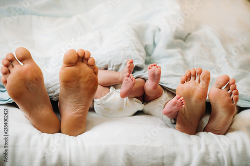 Fotografie the feet of parents and young children under the blanket
