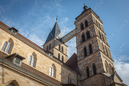Untersicht Türme der gotischen Stadtkirche St Dionys in Esslingen am Neckar mit Verbindungsbrücke zur Stabilisierung vor blauem Himmel mit Wolken