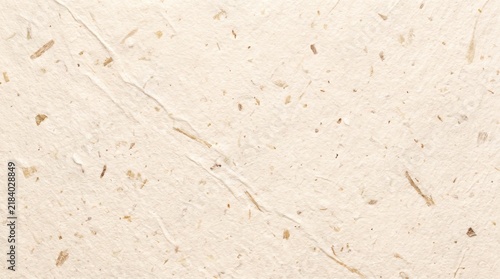 Beige recycled paper texture with natural fiber flecks and rough organic surface pattern