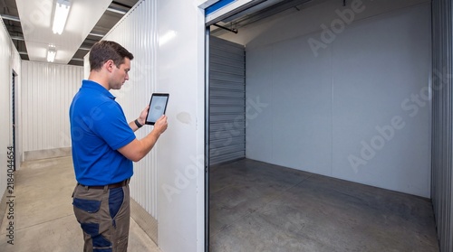 Manager using digital tablet to check vacant storage unit