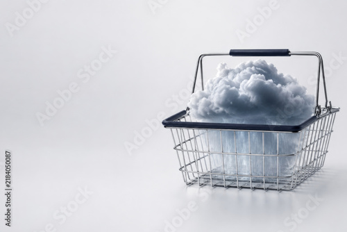 Rain cloud pours inside a metal shopping basket. Space for text.