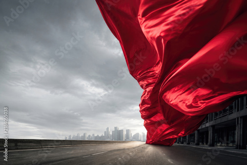 Large red fabric billows above an empty city road. Space for text.