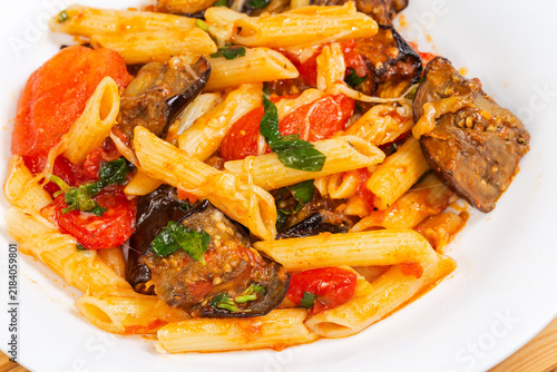 Pasta with eggplants, tomatoes, basil and grated cheese close-up