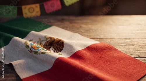 Mexican flag on wooden table with colorful festive decorations for Día de la Independencia de México holiday background with space for text