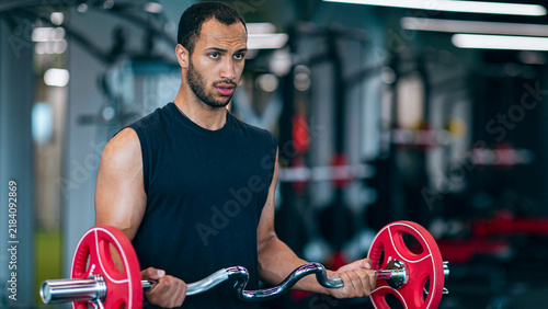 Obraz na płótnie Focused African American Man Engaged In Weight Lifting At Gym, Demonstrating Strength And Determination While Training