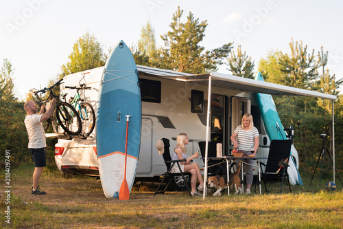 Fotografie A happy family is resting nearby near their motorhome in the forest
