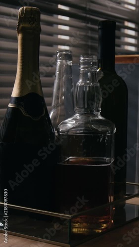 Vertical video of various alcohol bottles including whiskey decanter and wine standing on tray. Footage suitable for addiction awareness campaigns or beverage industry marketing