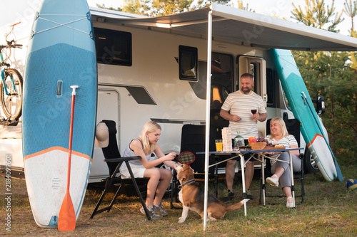 Fotografie A happy family is resting nearby near their motorhome in the forest