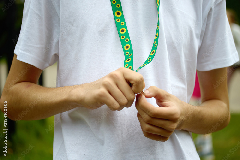 Naklejka premium Person's hands adjusting a green lanyard with sunflower pattern