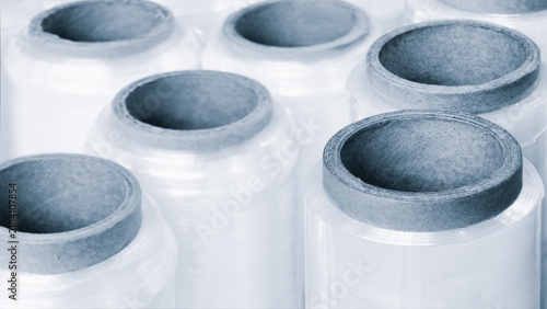 Rolls of polyethylene packaging film lie in row ready for packaging food products on packaging machine in an industrial factory, tech industrial technology background