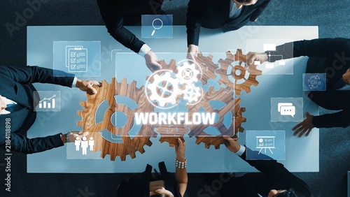 A group of professionals collaborates in an office setting, utilizing gears and digital graphics to enhance workflow management, focusing on efficiency and teamwork. Raster