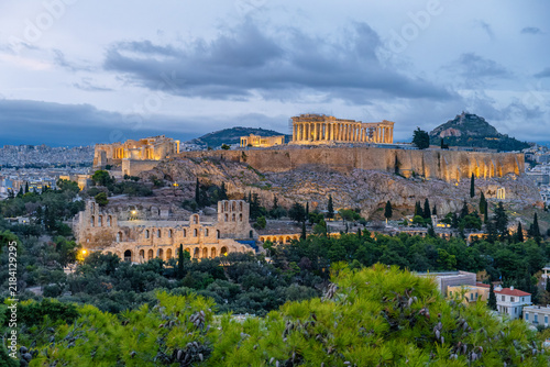 Evening view of Acropolis of Athens with illuminated Parthenon temple and Odeon of Herodes Atticus surrounded by the city. Greek travel destination for tourism, architecture, history, city breaks