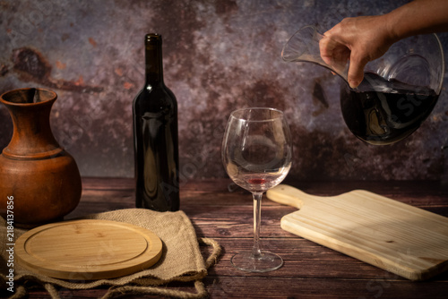 Foto Hand pouring decanted red wine into a glass