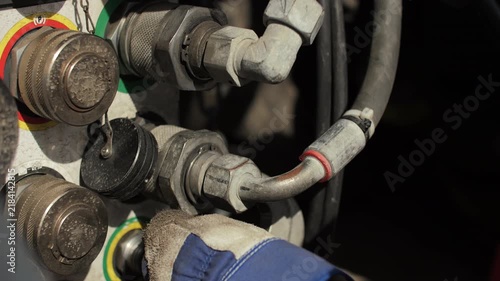 Worker tightening hydraulic coupling with wrench on heavy transport platform
