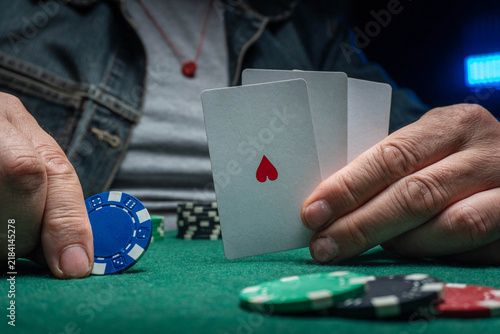 In a lively poker game at a bustling casino, players focus intently on their cards. The atmosphere is charged with suspense as bets are placed and chips stack up around the table