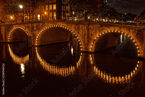 Canvas Print Amsterdam at night in the Grachtengordel with lights over entrances of bridge fo