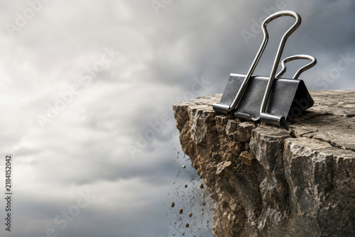Binder clips rest near the edge of a crumbling rock. Space for text.