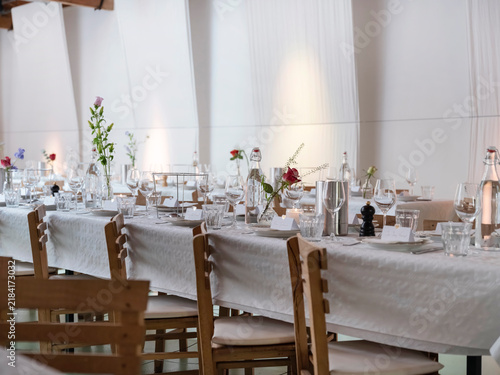 Konstfotografi Rows of dressed tables with small flower vases, swing top bottles, steel wine coolers and tea lights waiting for a group of guests