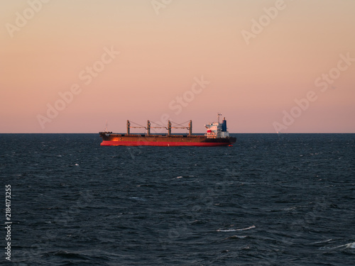 Konstfotografi A large bulk carrier cargo ship anchored calmly in Tallinn Bay during a colorful sunset, captured from a high aerial drone perspective