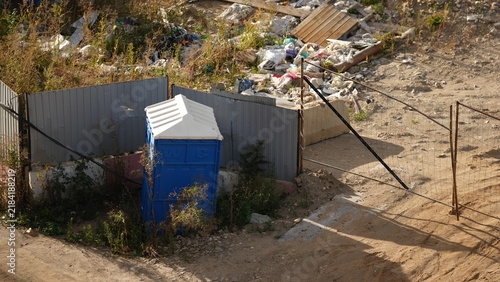 Canvastavla Portable outdoor toilet located near accumulated waste, highlighting sanitation