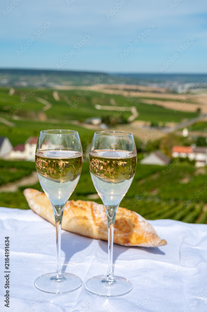 Obraz premium Champagne sparkling wine tasting in glasses with view on Grand Cru Blanc de Blancs Chardonnay vineyards of Cramant, France.
