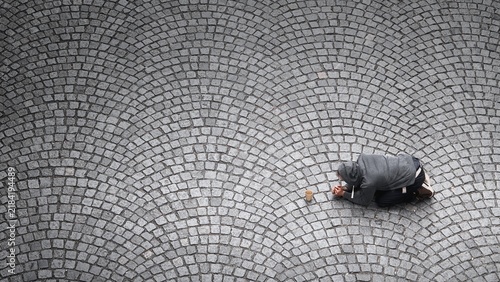 Konstfotografi Overhead view of a man begging with a paper cup on a cobblestone street in Prague, Czech Republic, illustrating poverty, hardship and social inequality