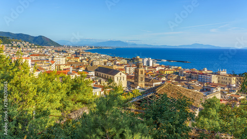 Scenic view of Salerno, Italy, showcasing coastal cityscape with Mediterranean Sea, mountains, and vibrant buildings under clear blue sky, ideal for exploring Amalfi Coast