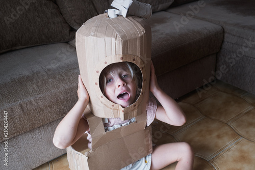 Fotografie Girl Wearing a Homemade Cardboard Costume Looking Surprised Indoors